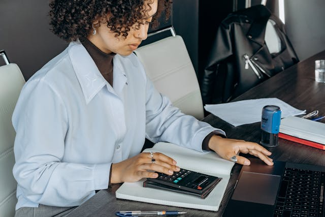 an-accountant-working-at-their-desk-and-using-a-calculator.png