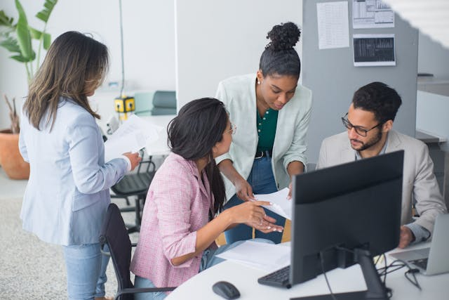 a-group-of-employees-working-at-a-desk-together.png